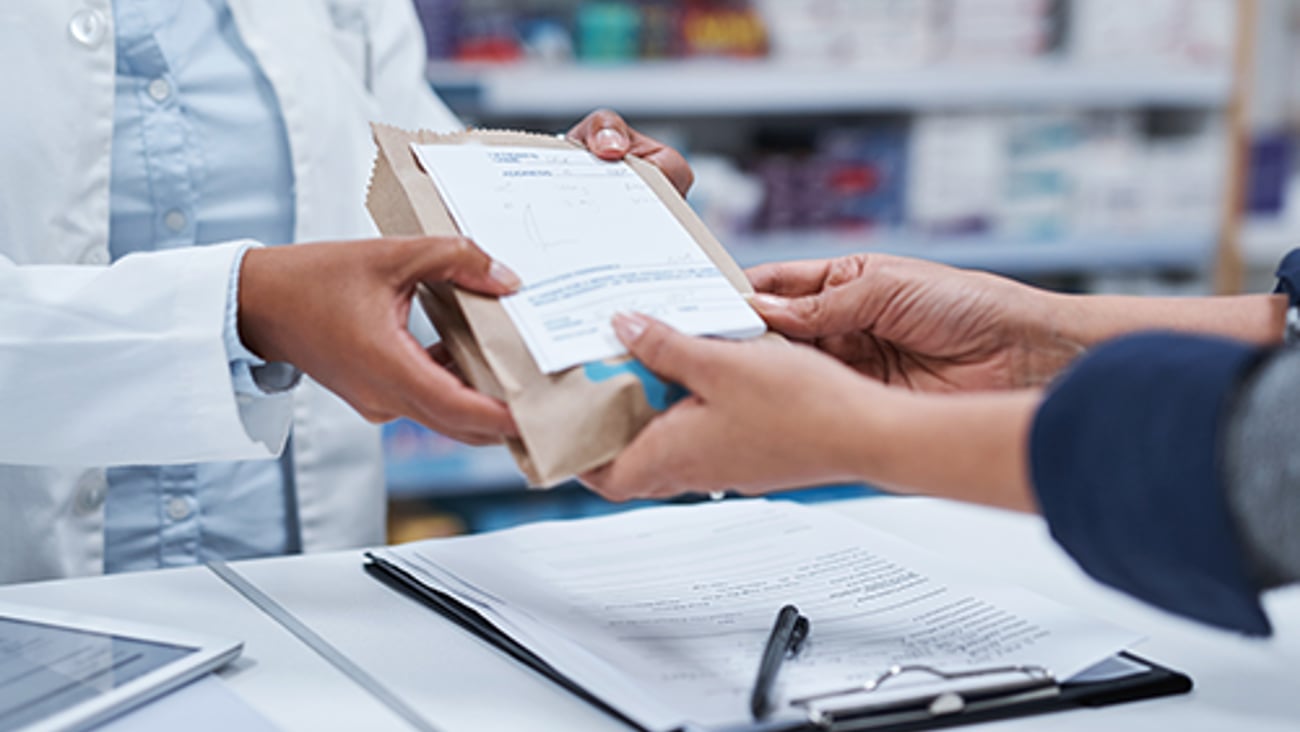 A pharmacist handing a prescription to a patient.