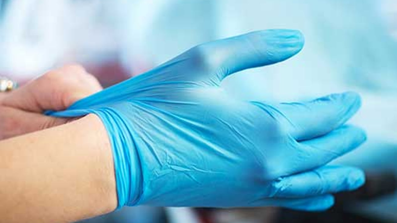 A healthcare worker putting on gloves. 