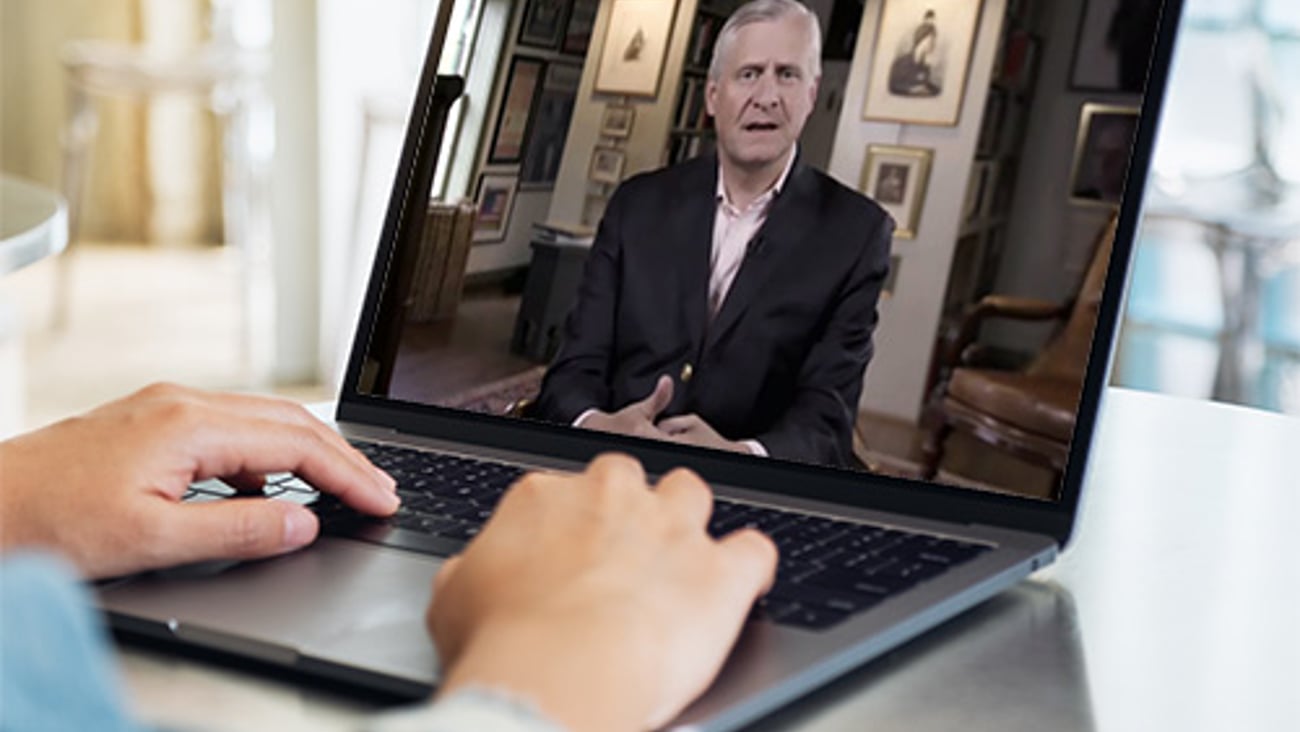 Jon Meacham et al. sitting at a desk and using a laptop computer