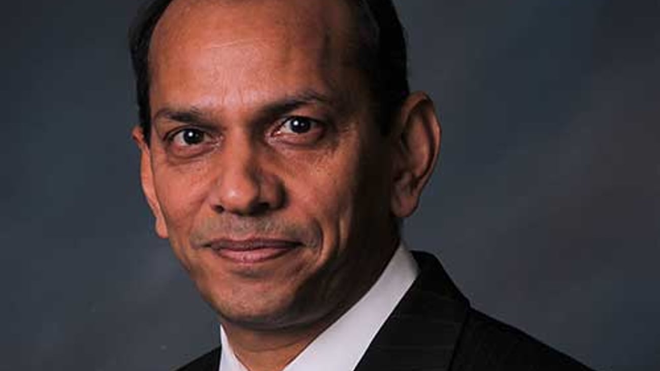 a man wearing a suit and tie smiling at the camera