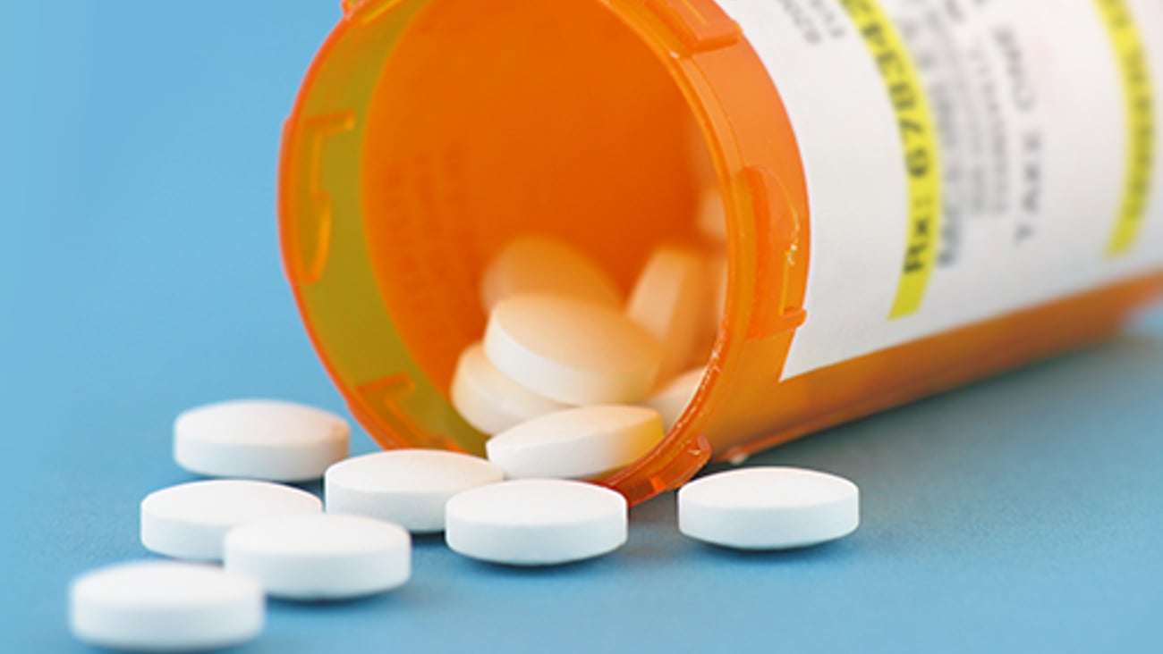 Generic white pills spilling out of a pill bottle.