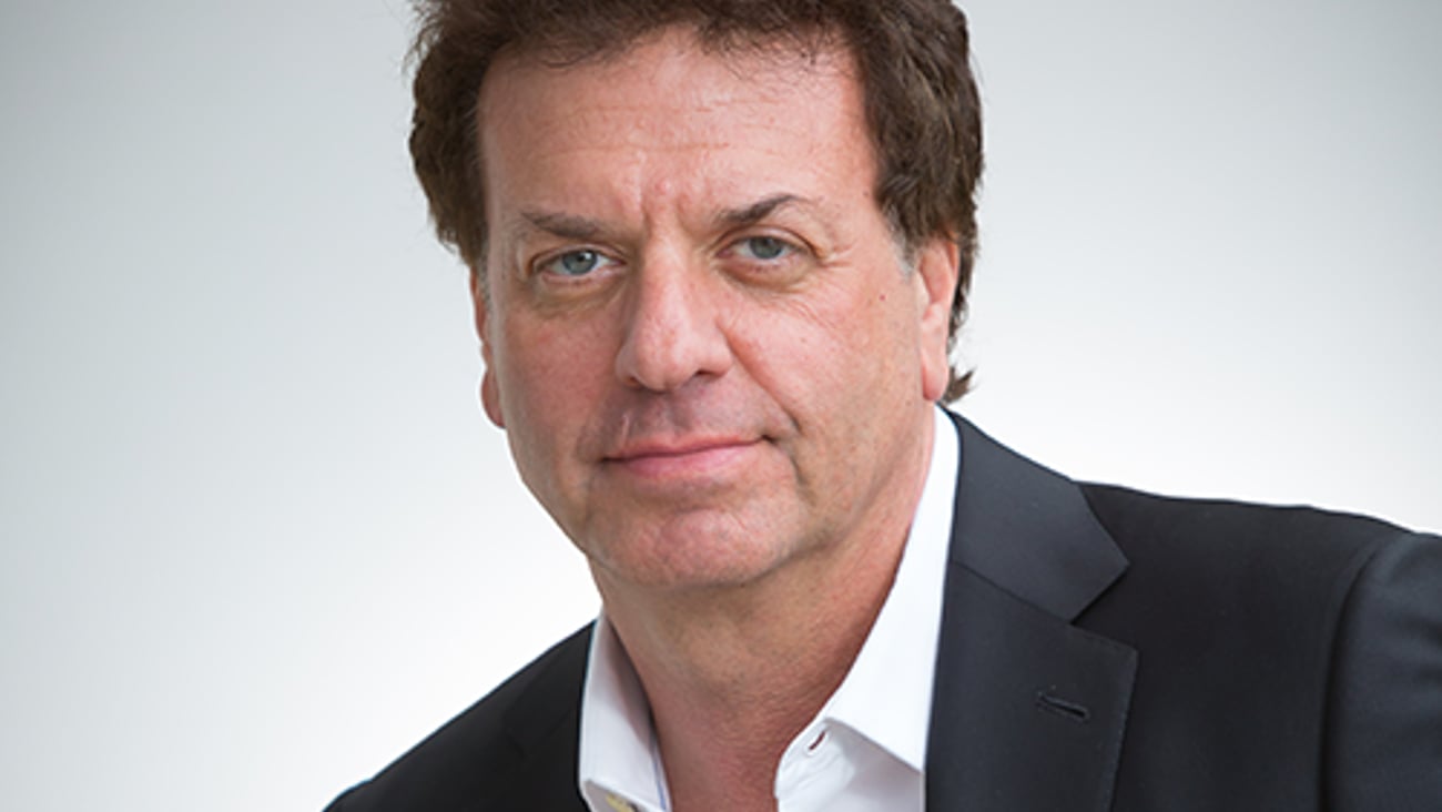 a man wearing a suit and tie smiling and looking at the camera