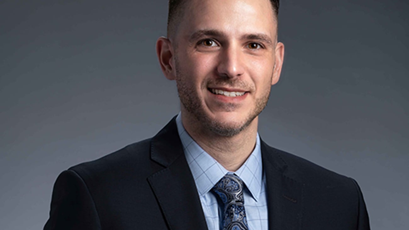 a man wearing a suit and tie smiling at the camera