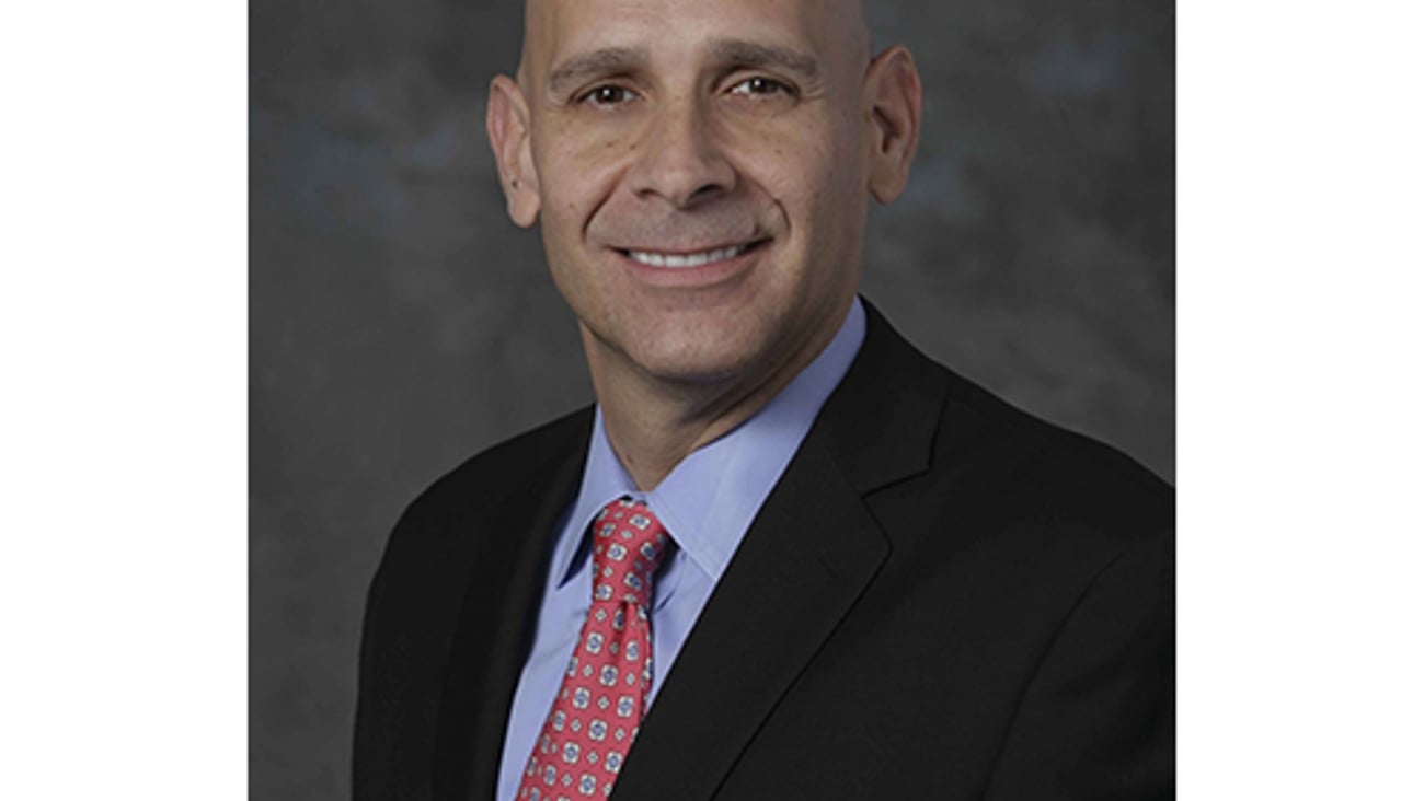 a man wearing a suit and tie smiling at the camera