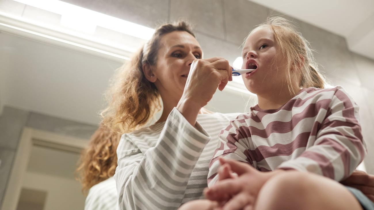 woman brushing child's teeth