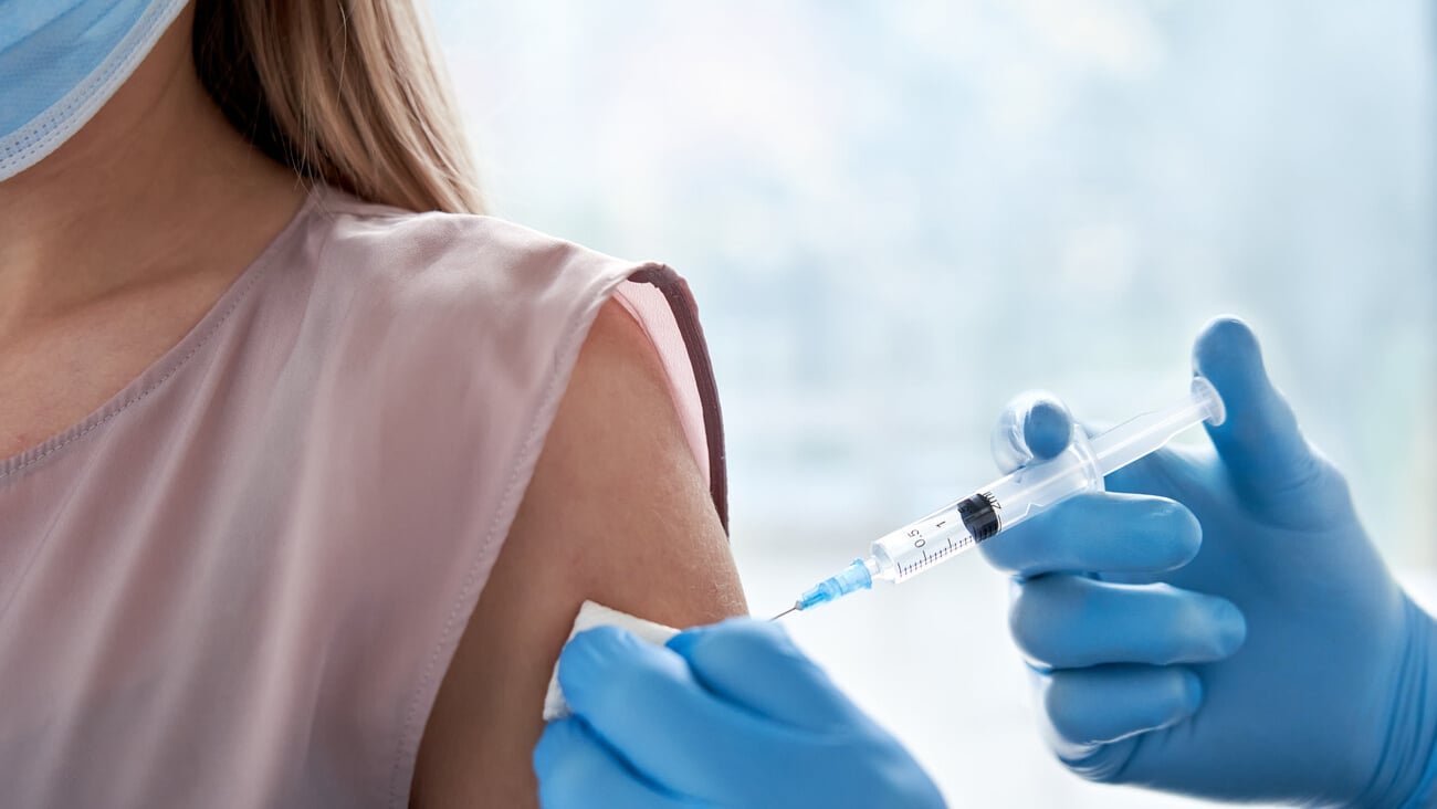 Male doctor holding syringe making covid 19 vaccination injection dose in shoulder of female patient. Flu influenza vaccine clinical trials concept, corona virus treatment side effect, inoculation. ; Shutterstock ID 1859217856