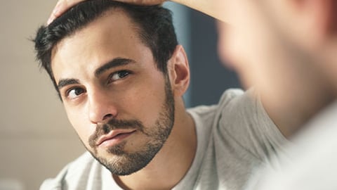 man inspecting hair for loss