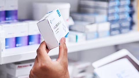 A pharmacist holding a prescription box.