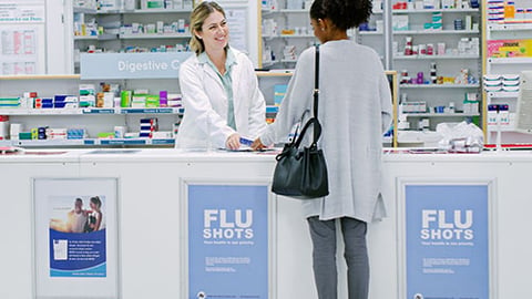 A pharmacist handing a prescription to a patient.