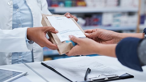 A pharmacist handing a prescription to a patient.