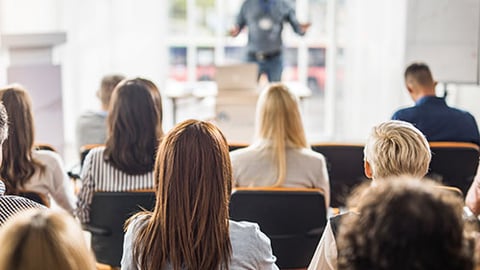 A conference full of peoples sitting in front of a speaker.