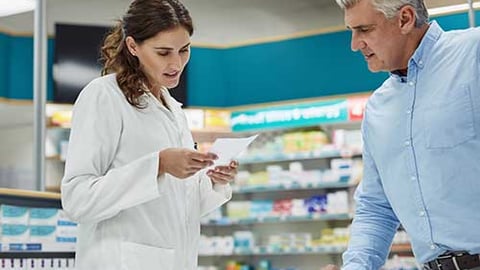 A female pharmacist and a male patient at the counter.