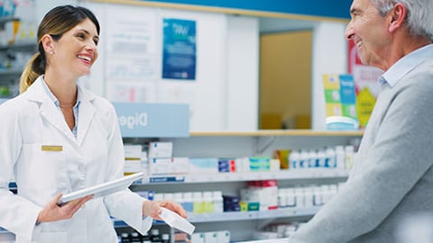 A pharmacist handing a prescription to a patient.