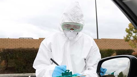 A healthcare worker giving a test to a person in a car.