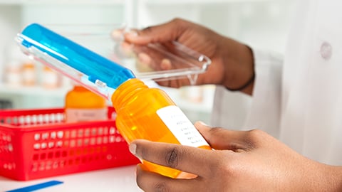 A pharmacist putting pills in a bottle.