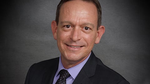 a man wearing a suit and tie smiling at the camera