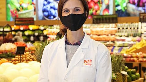 a man standing in front of a store filled with lots of fresh produce