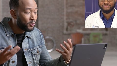 John Legend et al. sitting at a table using a laptop computer