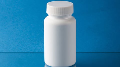 A white pill bottle against a blue background.