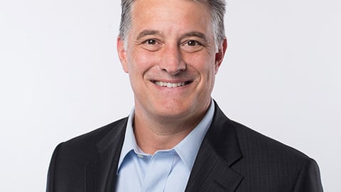 John King wearing a suit and tie smiling at the camera