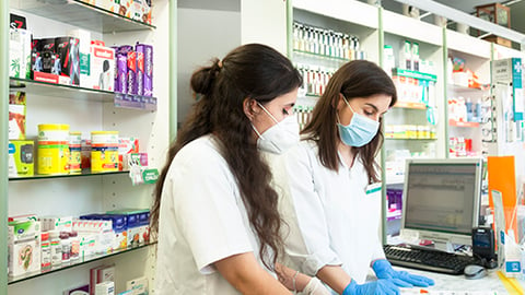 Two pharmacists at a computer in a pharmacy.