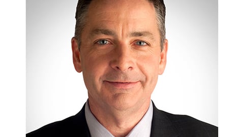 a man wearing a suit and tie smiling at the camera