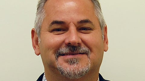 a man wearing a suit and tie smiling and looking at the camera