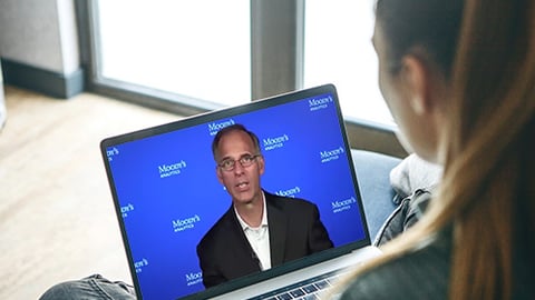 Mark Zandi sitting at a desk in front of a laptop computer