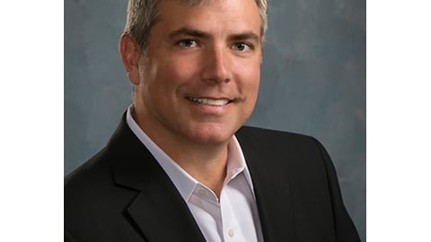 a man wearing a suit and tie smiling at the camera