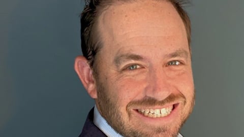 a man wearing a suit and tie smiling and looking at the camera