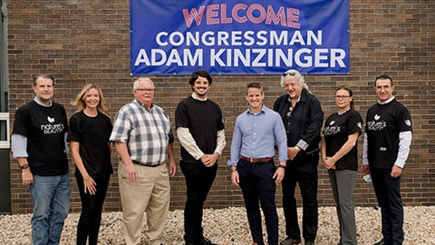 a group of people standing in front of a sign posing for the camera