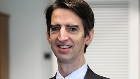 a man wearing a suit and tie smiling at the camera