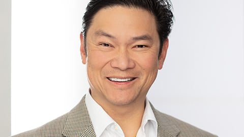 a man wearing a suit and tie smiling at the camera