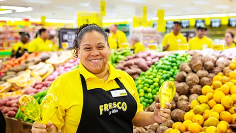 a person standing in front of a store filled with lots of fruit