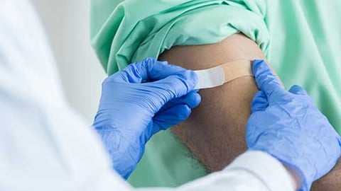 A healthcare working putting a bandaid on an arm after immunizatin.