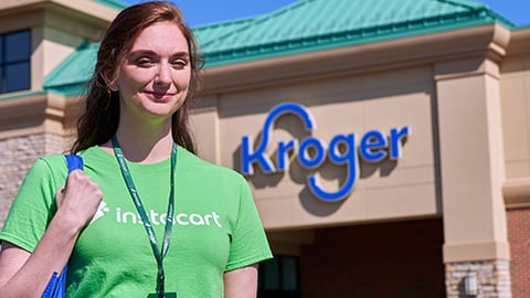 a smiling man in a green shirt standing in front of a building