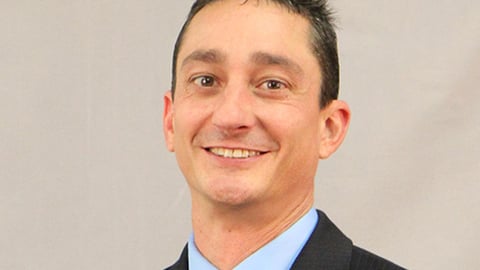 a man wearing a suit and tie smiling at the camera