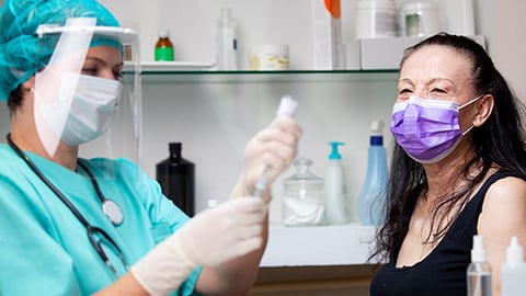 pharmacist getting vaccine ready to give to woman