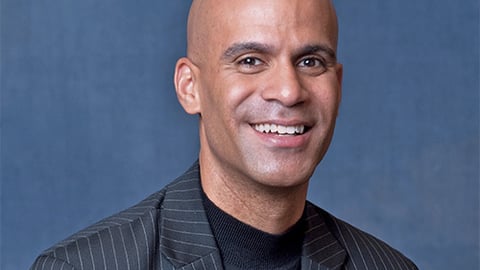 a man wearing a suit and tie smiling at the camera