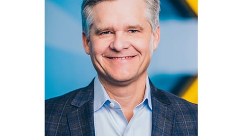 a man wearing a suit and tie smiling at the camera