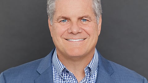 a man wearing a suit and tie smiling at the camera