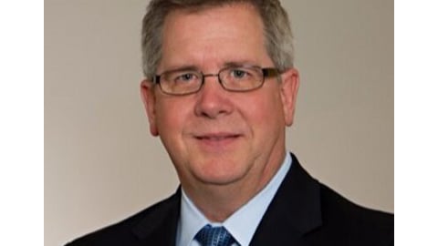 a man wearing a suit and tie smiling at the camera