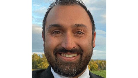 a man wearing a suit and tie smiling at the camera