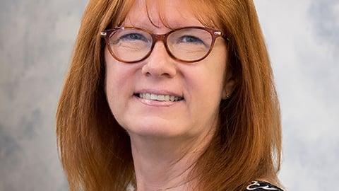 a close up of a person wearing glasses and smiling at the camera