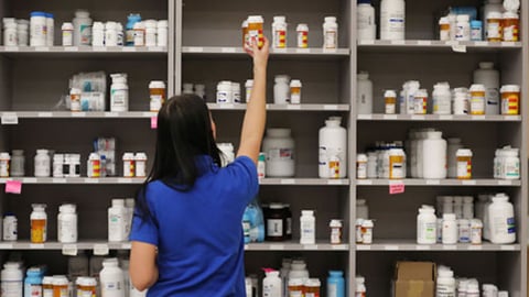 Pharmacy technician reaching for medication