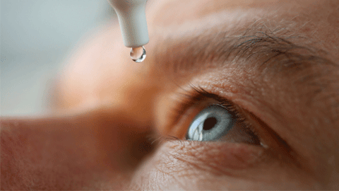 man putting drops in eye