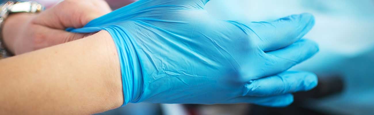 A healthcare worker putting on gloves. 