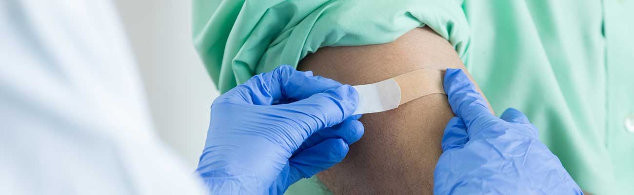 Healthcare worker putting a bandaid on patient's arm.