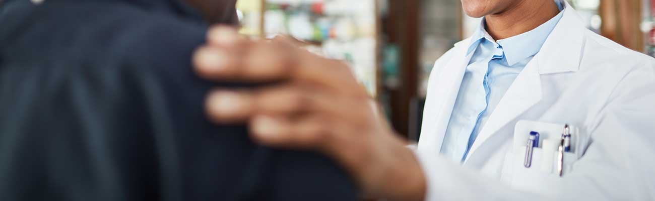 A pharmacist with hand on a patient's shoulder.