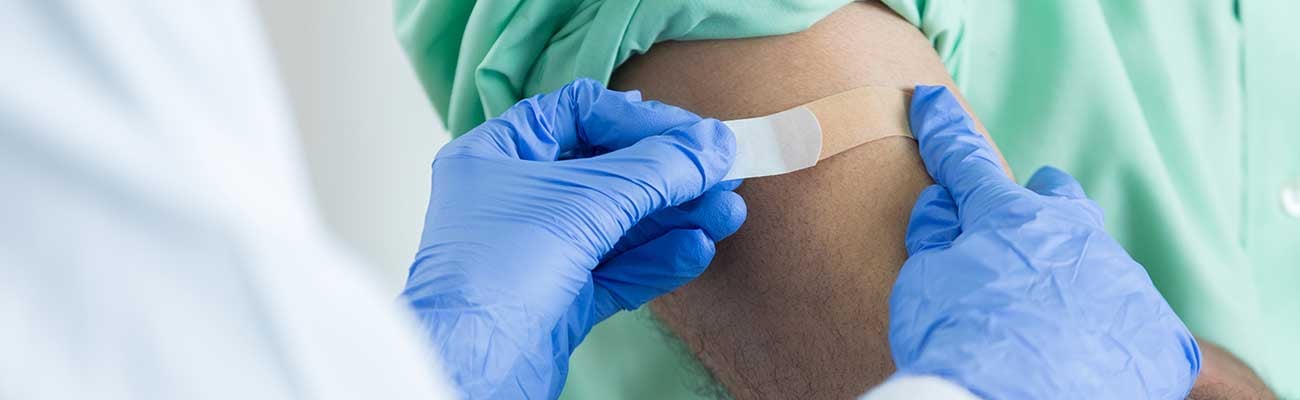 A healthcare worker putting bandaid on arm.